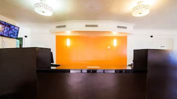 A reception area with a modern design, featuring a central counter and two symmetrical seating areas.