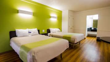 A hotel room with two beds, a green wall, and a wooden floor.