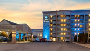 A hotel with multiple floors, a prominent 'Best Western' sign, and a parking area with several cars.