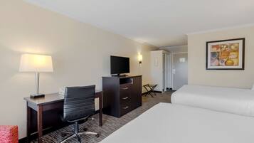 Habitación de hotel con cama, escritorio, silla, televisor y un cuadro en la pared.