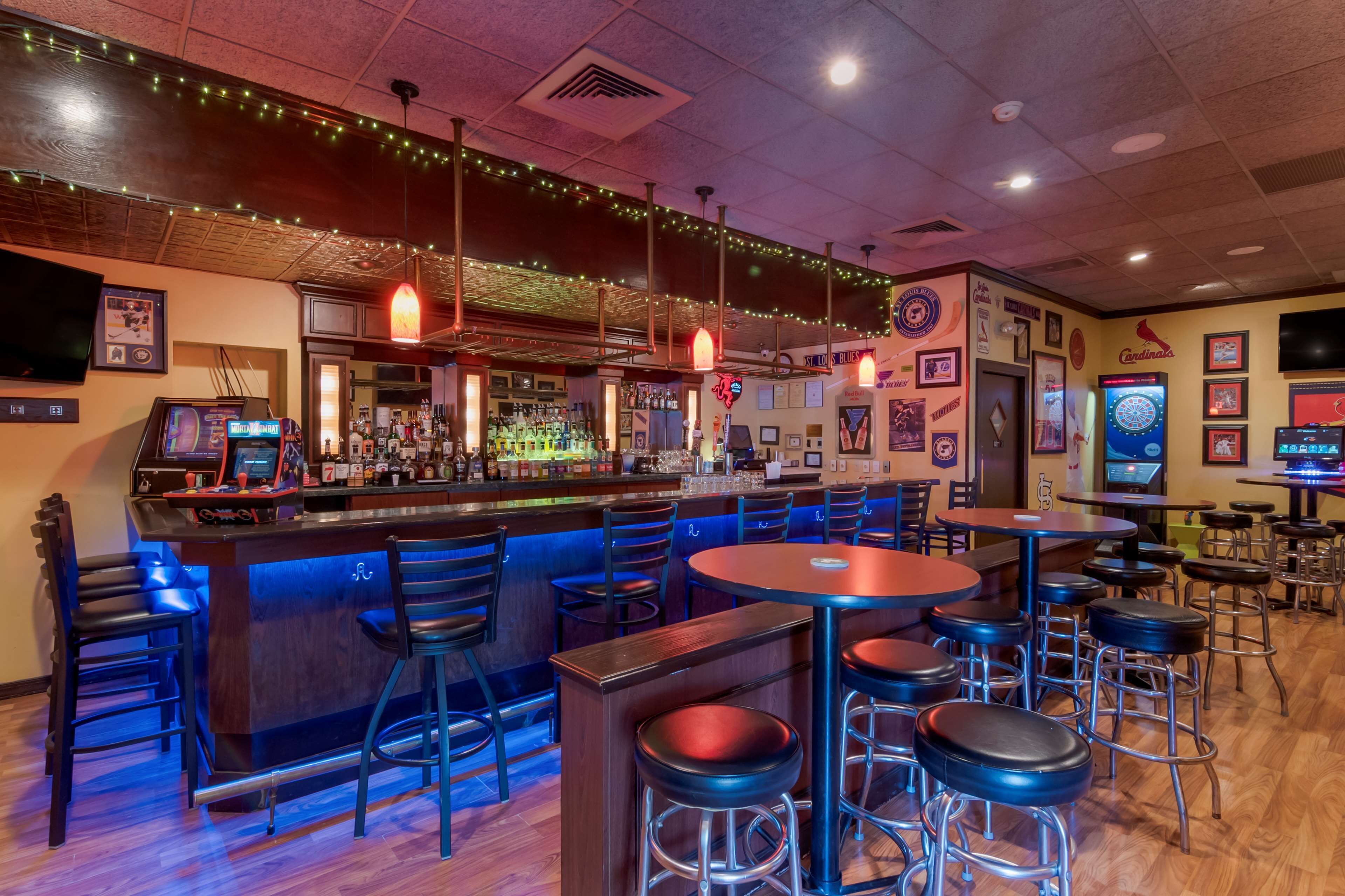 A bar area with stools, a counter with bottles, and a dartboard.