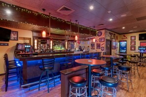 A bar area with stools, a counter with bottles, and a dartboard.
