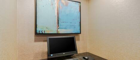 A computer desk with a monitor, keyboard, and mouse.