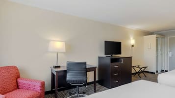 Een hotelkamer met een bed, een bureau met stoel, een televisie, een lamp en een kledingkast.