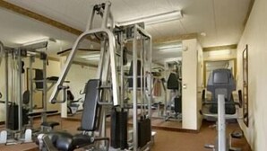 A gym with various exercise machines, mirrors, and weights. - Travelodge by Wyndham Parsippany (Parsippany)