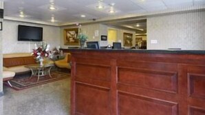 A hotel lobby with a reception desk, seating area, and a television mounted on the wall. - Travelodge by Wyndham Parsippany (Parsippany)