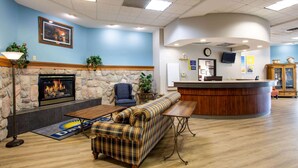 Eine Lobby mit Kamin aus Stein, blauer Wand, einer Rezeption und einer Sitzecke mit kariertem Sofa und Bank.