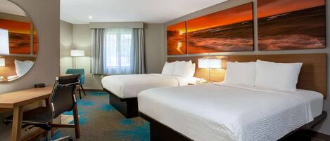 A hotel room with two beds, a desk, a chair, and a large mirror.