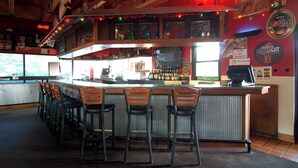 Eine Bar mit einer Theke, Barhocker und verschiedenen Spirituosenflaschen.