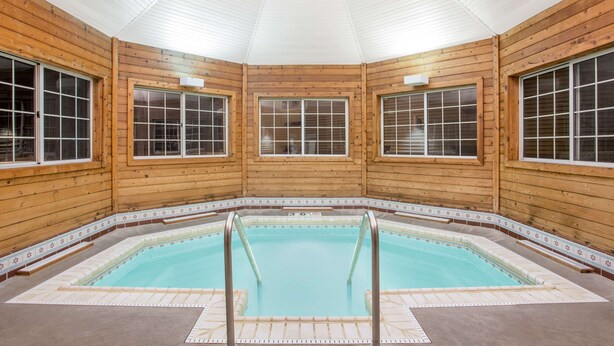 Eine Holzhütte mit Pool, großen Fenstern und Fliesenboden.