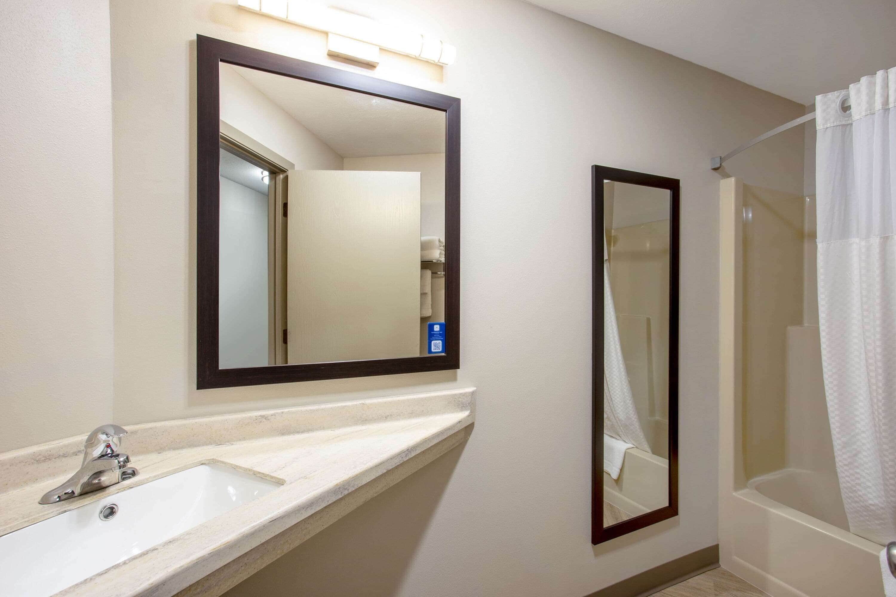 A bathroom with a sink, mirror, and shower.