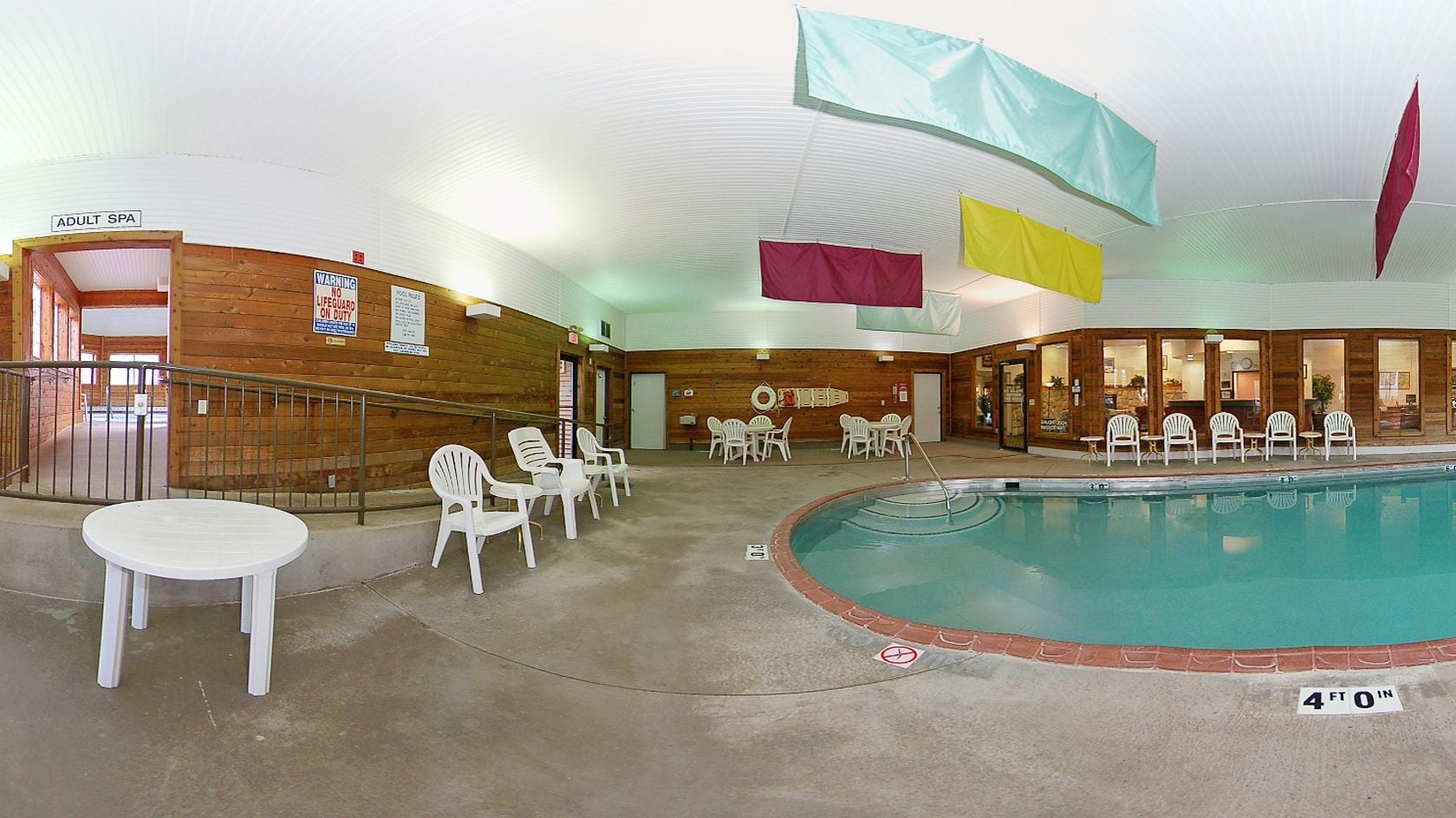 An indoor pool area with a wooden interior, white chairs, and a sign indicating 'ADULT SPA'.
