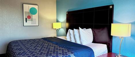 A hotel room with a large bed, two bedside lamps, a nightstand, and a wall art piece.