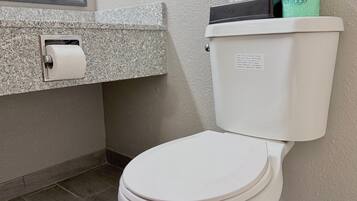 A white toilet with a paper towel holder and a green toilet paper roll on top.