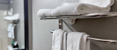 A bathroom with a towel rack holding two folded towels and a mirror above it.