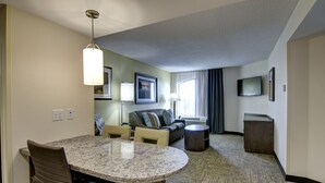 Une chambre d’hôtel comprenant un coin repas, un canapé, une télévision et une petite table.