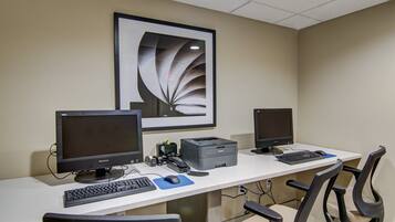 A workspace with two monitors, a keyboard, a mouse, a printer, and office chairs.