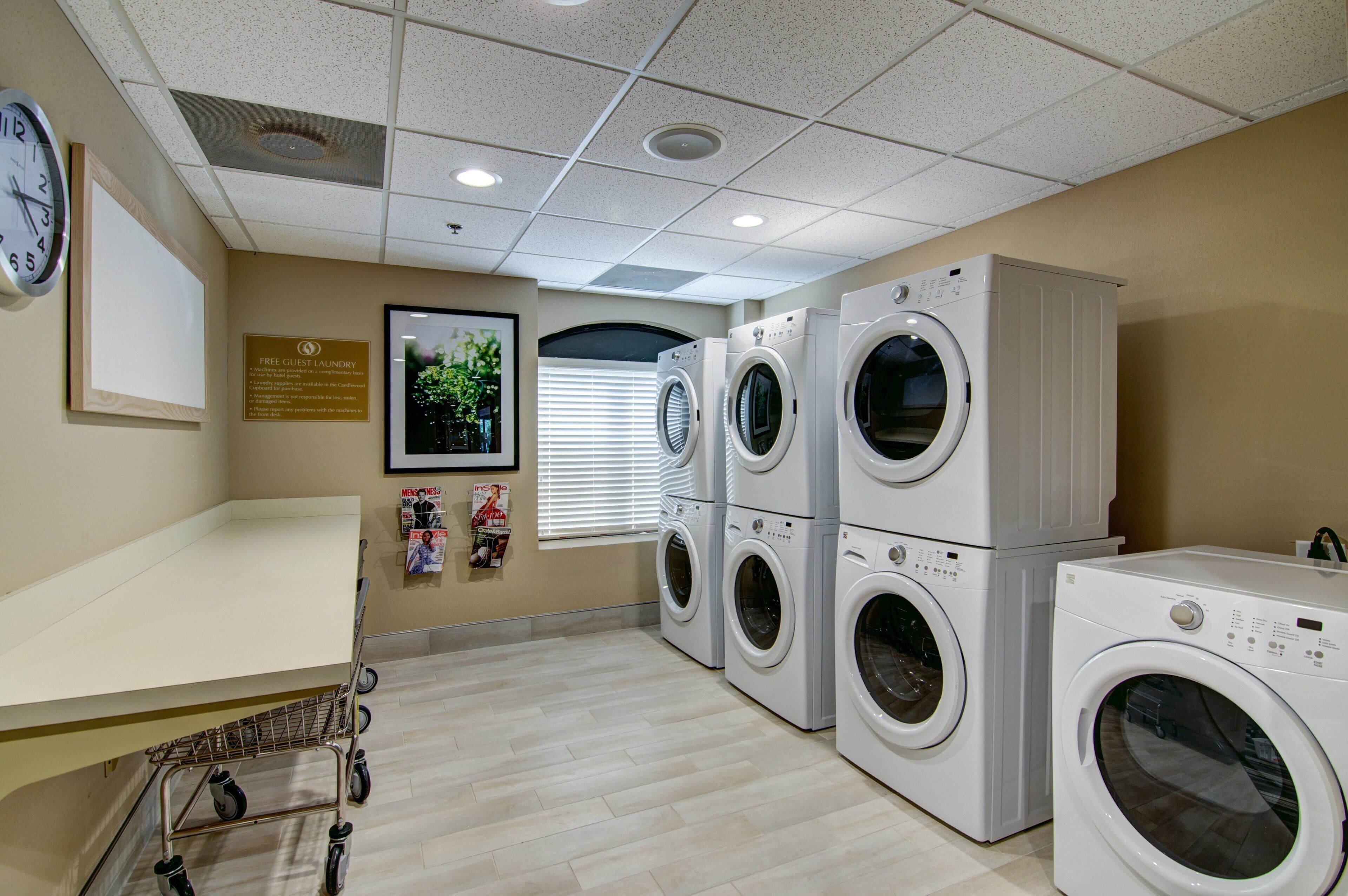 A laundry room with multiple washing machines, a clock, and a sign indicating free guest laundry.