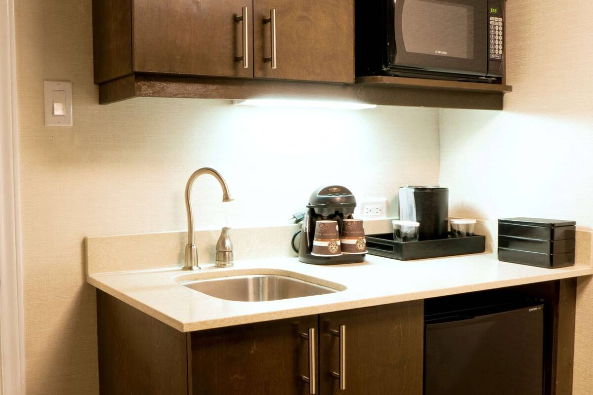 A compact kitchen with a stainless steel sink, a coffee maker, a microwave, and a dishwasher.