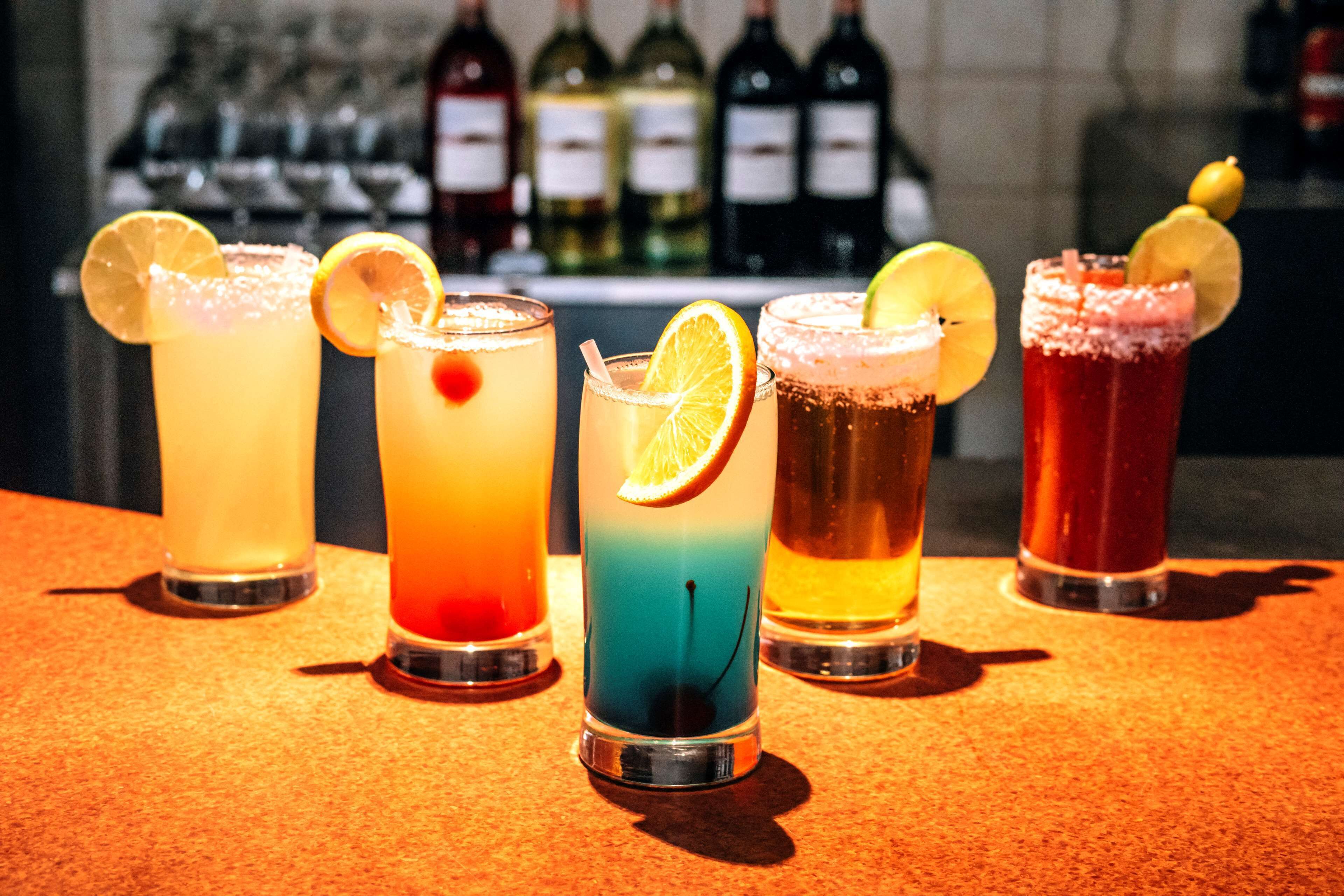 A bar with five different cocktails, each garnished with a slice of fruit.