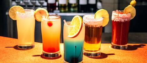 A bar with five different cocktails, each garnished with a slice of fruit.