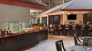 Una cucina moderna con una colazione bar, un'area pranzo con sgabelli da bar e una TV a schermo piatto montata a parete.