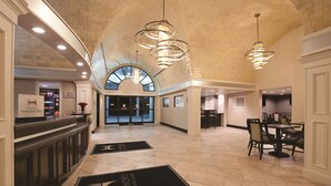 Un'ampia hall con soffitto alto, lampadari moderni e una reception.