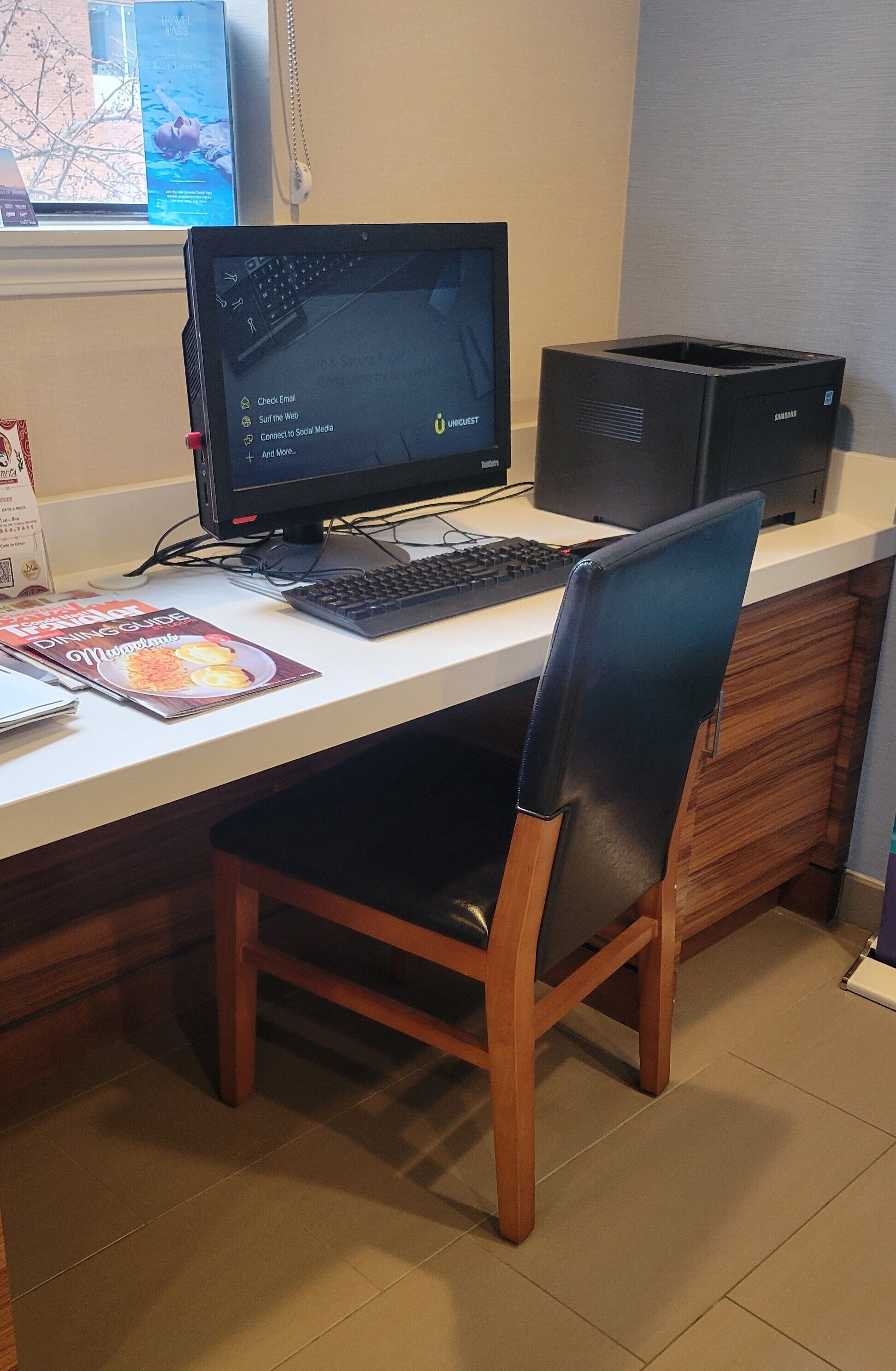A desk with a computer, keyboard, and a chair.