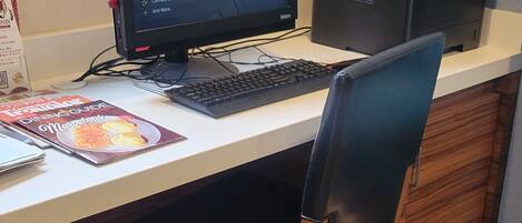 A desk with a computer, keyboard, and a chair.