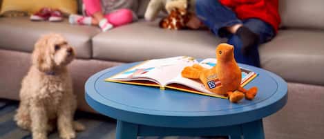 Una sala de estar con una mesa redonda azul, un sofá y dos niños jugando con juguetes.