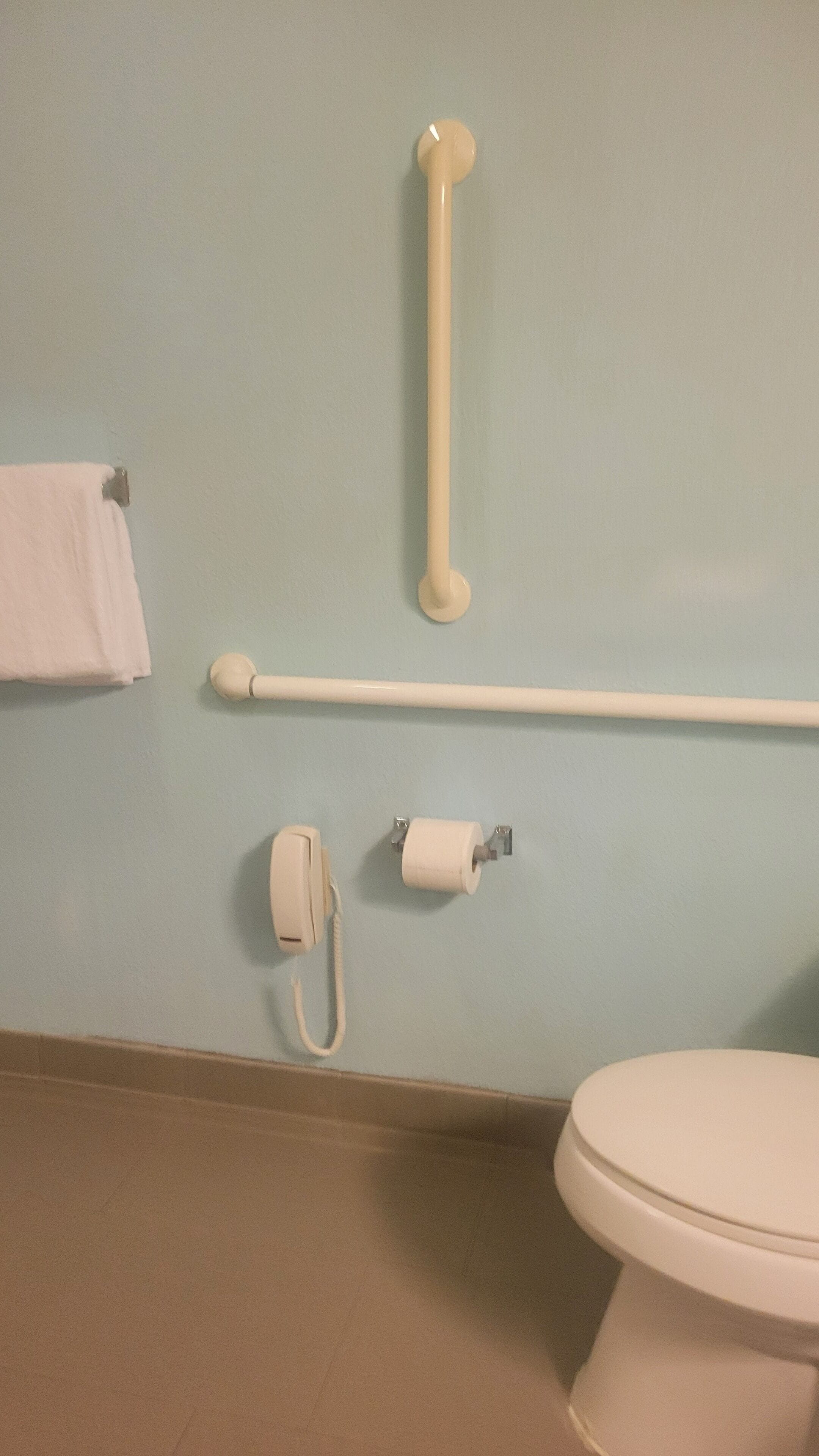 A bathroom with a toilet, a towel rack, a grab bar, and a toilet paper holder.
