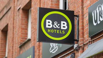 Een bord voor B&B Hotels met een cirkelvormig logo en de naam in witte letters op een zwarte achtergrond.