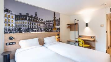 A hotel room with a large bed, a desk with a chair, a wall-mounted mirror, and a mural of a city street.