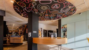 A modern lobby with a circular ceiling design, a reception desk, and a staircase leading to another level. - B&B Hotel Lille Roubaix Centre Grand-Place (Roubaix)