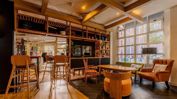 A cozy interior with wooden furniture, a bar area, and large windows. - B&B Hotel Lille Roubaix Centre Grand-Place (Roubaix)