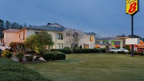 Un motel Super 8 avec une pelouse bien entretenue, une grande enseigne et un parking où sont garées plusieurs voitures.