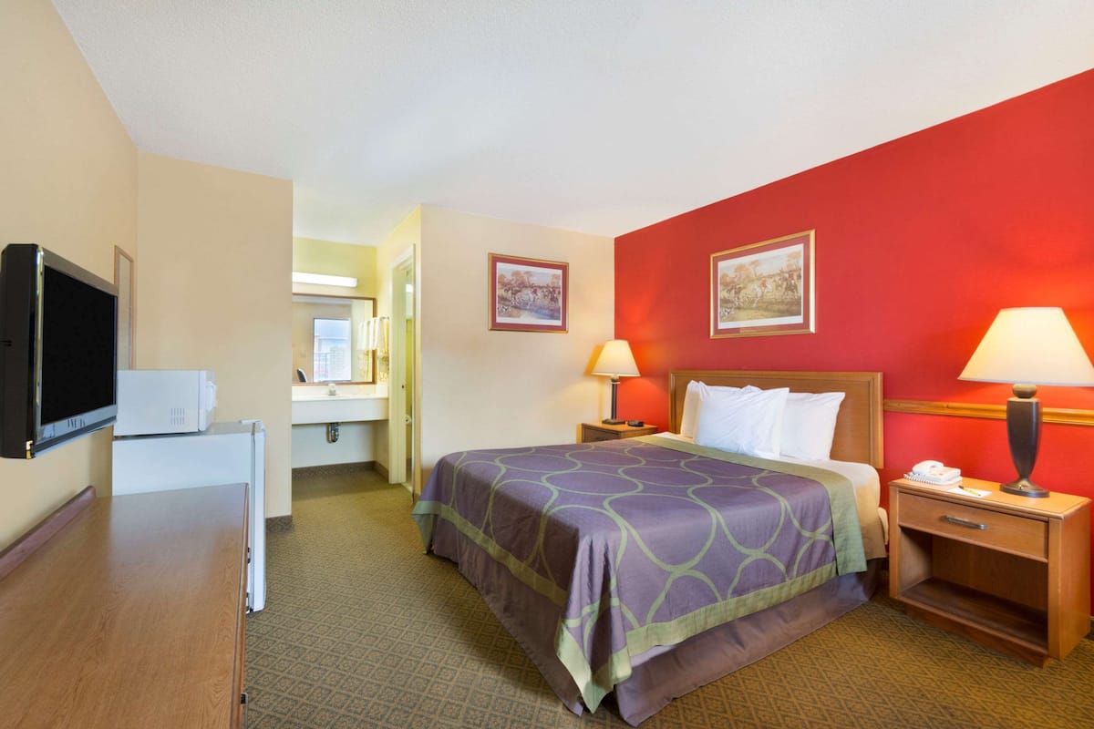 A hotel room with a bed, two bedside tables with lamps, a television, and a microwave.