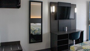 A hotel room with a bed, a desk with a chair, a TV, and a mirror. - Motel 6 Round Rock, TX (Round Rock)