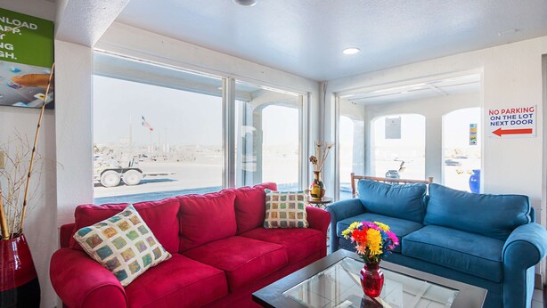 A room with two sofas, a glass coffee table, and a vase of flowers. - Motel 6 Round Rock, TX (Round Rock)