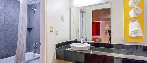 Un baño con bañera, inodoro, lavamanos y un espejo con un perchero amarillo.