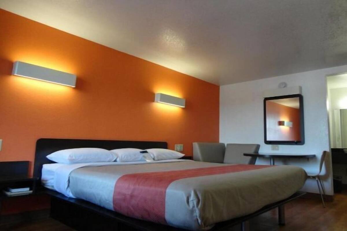 A hotel room with a bed, a desk, and a chair.