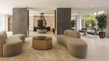 A spacious living area with modern furniture, large windows, and a central coffee table.
