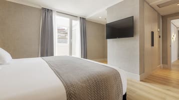 A modern hotel room with a large bed, a flat-screen TV mounted on the wall, and a sliding door leading to a bathroom.