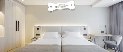 Quarto de hotel com cama de casal, mesas de cabeceira, escrivaninha e uma cadeira.