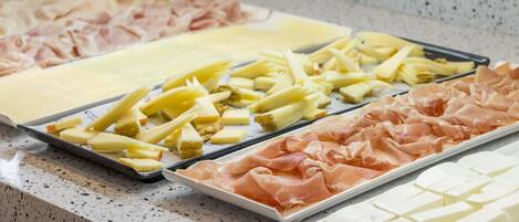 Un buffet proposant une variété de plats, notamment des viandes et des fromages.