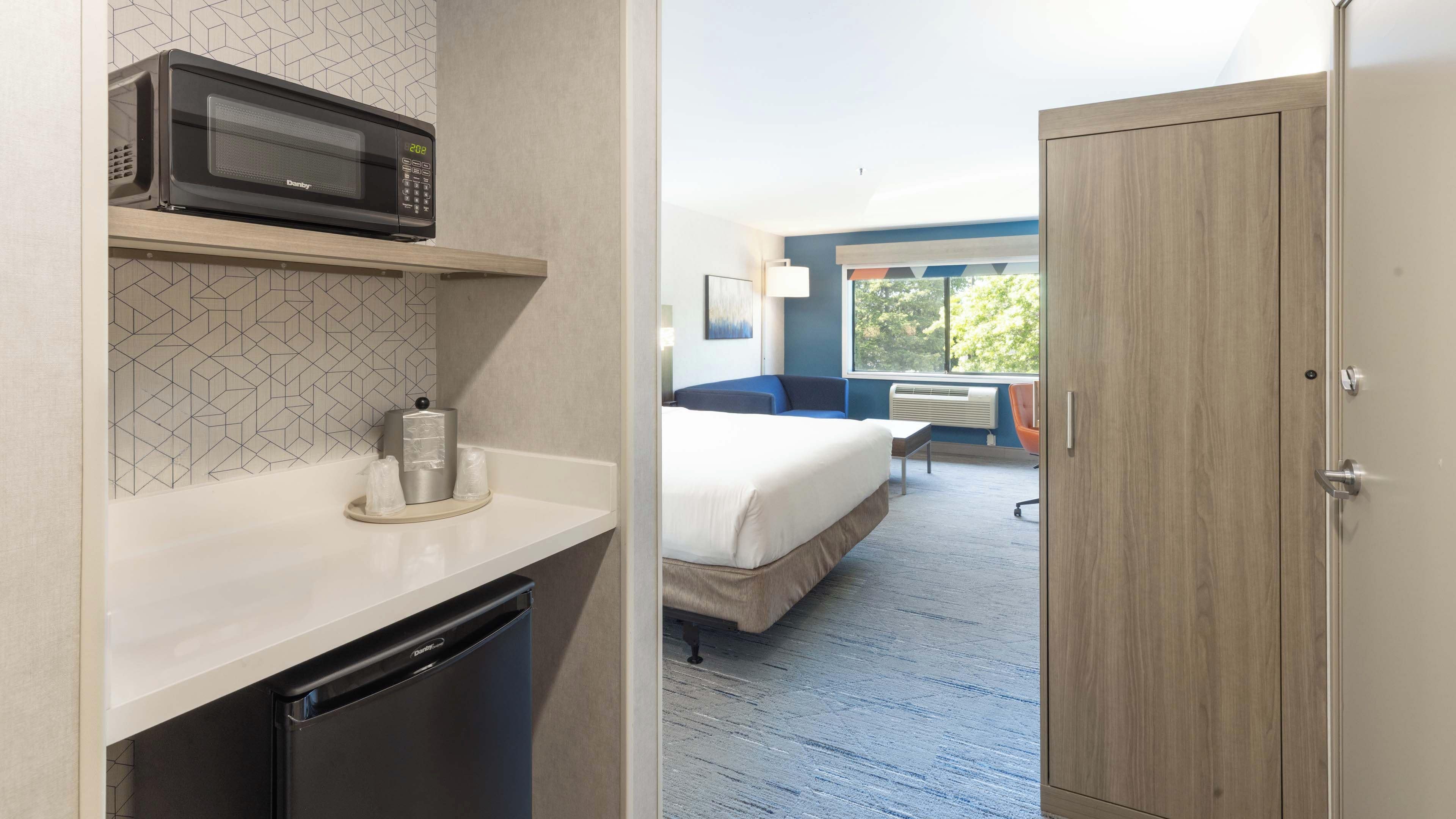 Ein Hotelzimmer mit Mikrowelle, kleinem Kühlschrank, einem Bett, einem Schreibtisch und Blick ins Freie.