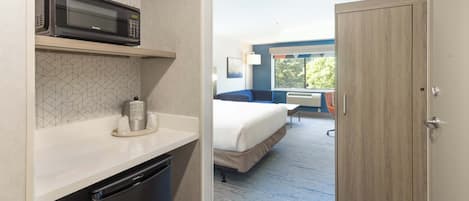 Ein Hotelzimmer mit Mikrowelle, kleinem Kühlschrank, einem Bett, einem Schreibtisch und Blick ins Freie.
