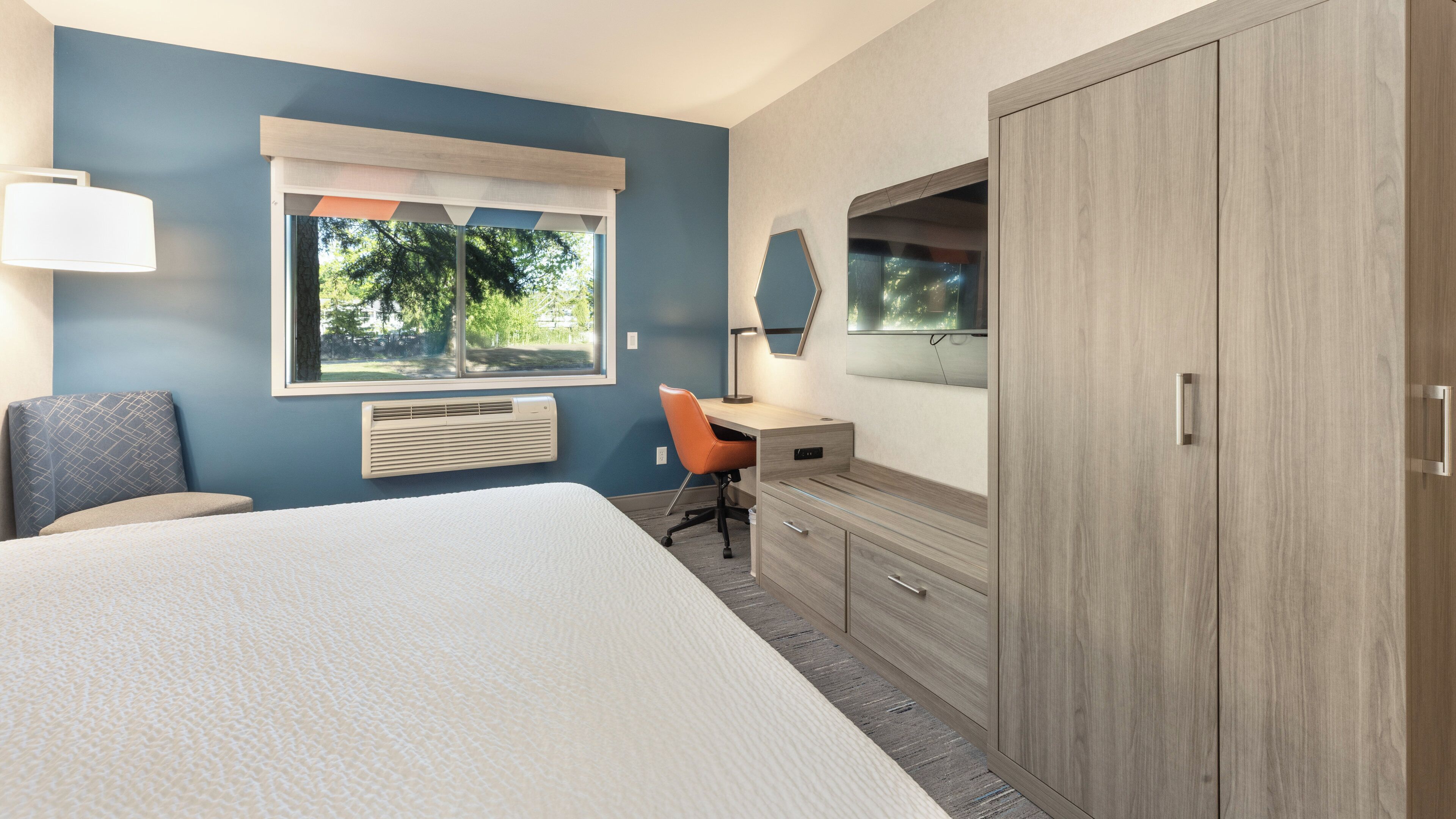 A bedroom with a large bed, a desk, and a wardrobe.