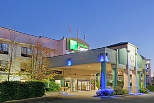 Un hotel Holiday Inn Express con una fachada moderna, amplias puertas de entrada y una zona de acceso bien iluminada.