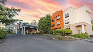 A Holiday Inn Express hotel with a modern design, featuring a mix of orange and white buildings, a covered entrance, and well-maintained landscaping.
